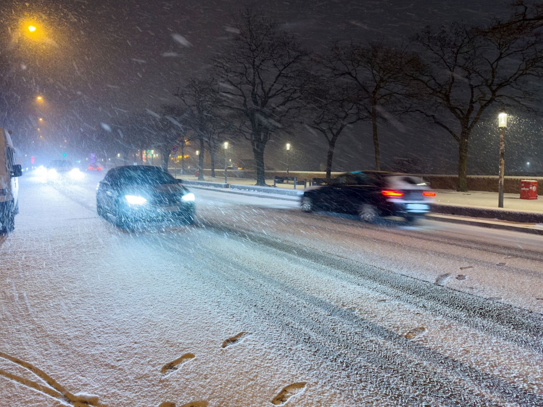 Schnee fällt am späten Samstagabend (24. Januar) auf einer Straße am Hafen in Hamburg.