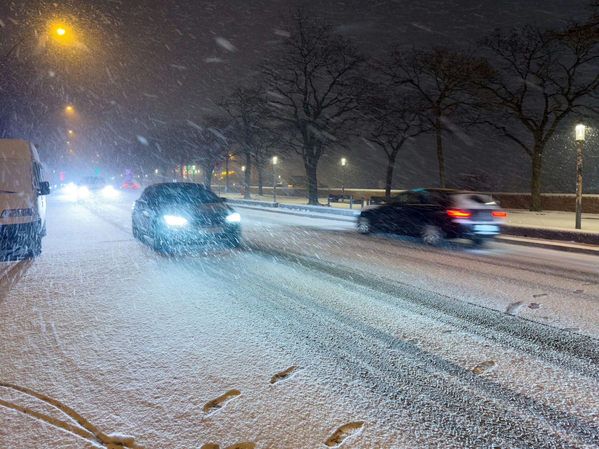 Schnee fällt am späten Samstagabend (24. Januar) auf einer Straße am Hafen in Hamburg.
