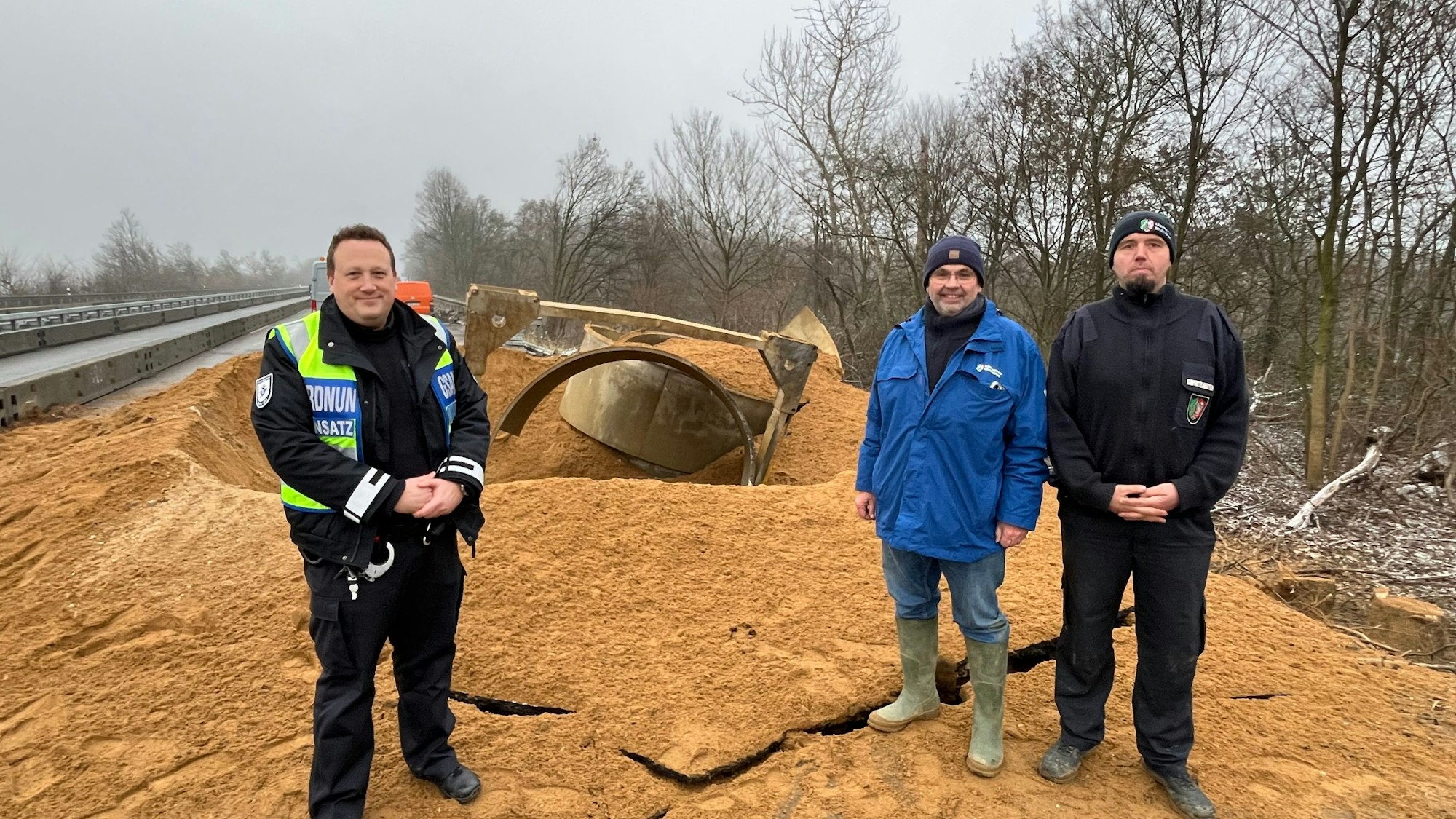 Das Foto zeigt Johannes Brauns (Kommunale Ordnungsdienst Stadt Köln), Dirk Putzer (Einsatzleiter Kampfmittelbeseitigungsdienst Bezirksregierung Düsseldorf), Markus Schmitz (ebenfalls Kampfmittelbeseitigungsdienst) am Fundort des Blindgängers nach der Sprengung.