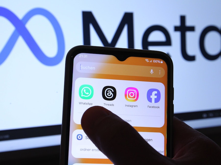 Hand hält Smartphone mit Apps vor Bildschirm