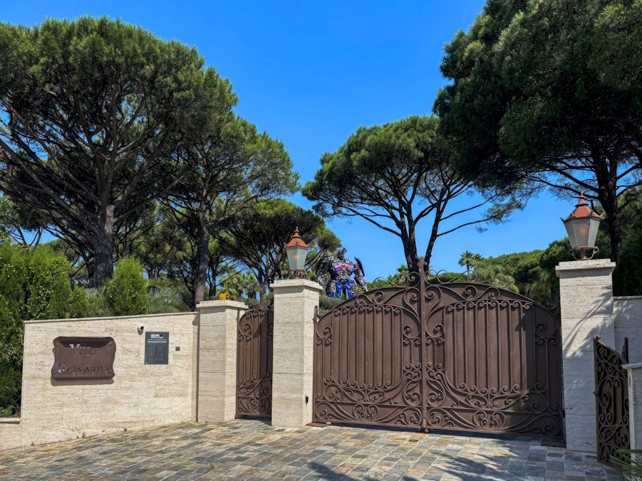 Eingangstor einer Villa mit Bäumen und Figur