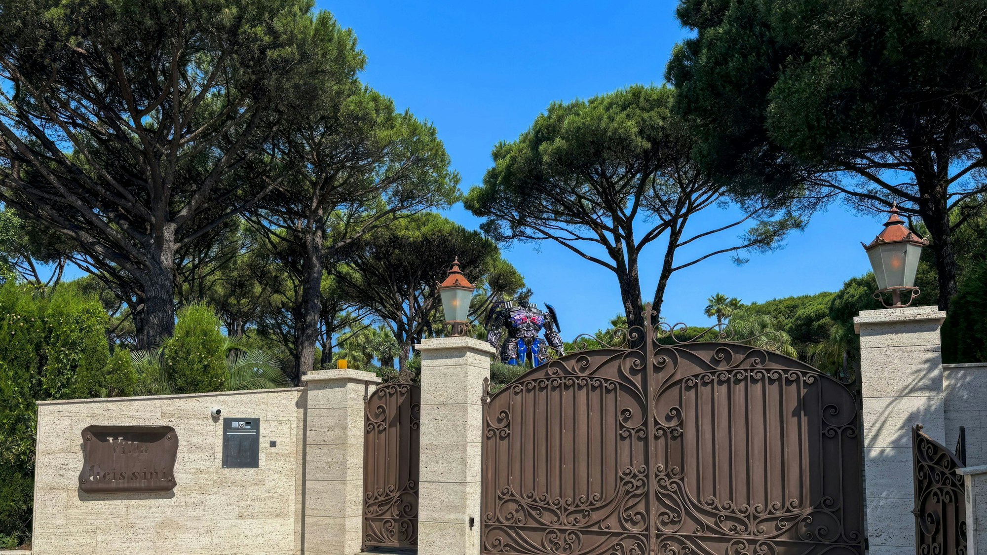 Eingangstor einer Villa mit Bäumen und Figur