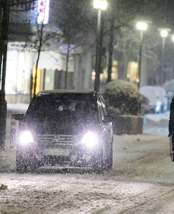 Radfahrer fährt neben Autos über eine schneebedeckte Straße.