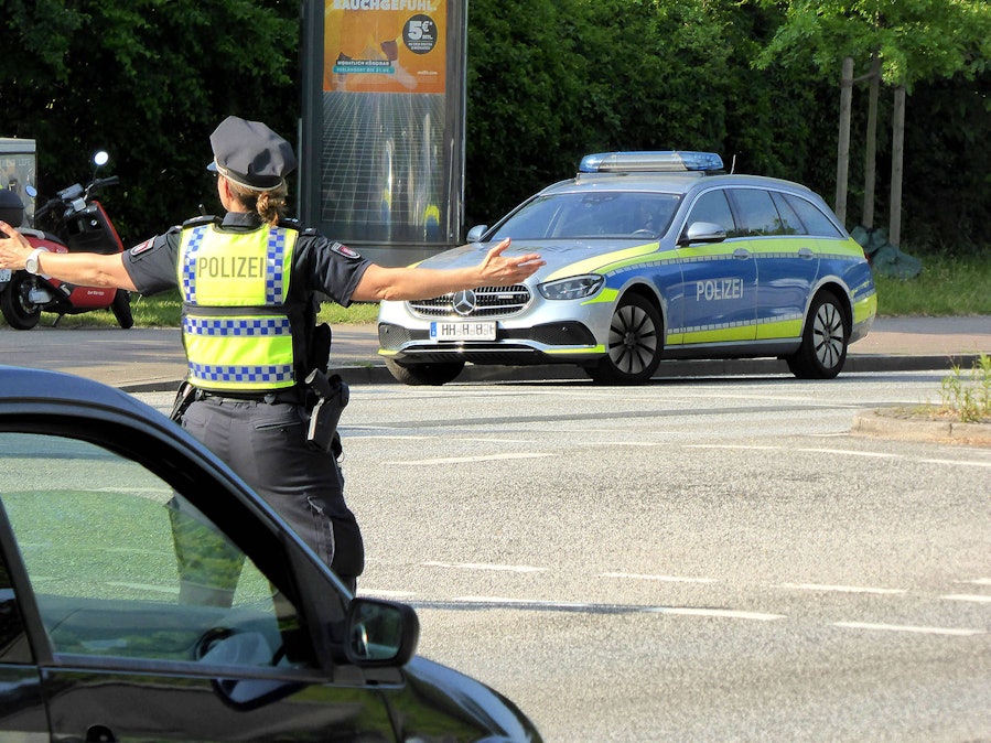 Polizistin regelt Verkehr, Polizeifahrzeug auf Strasse