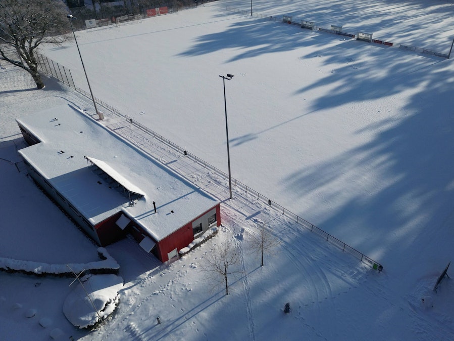 Vollständig verschneiter Sportplatz mit angrenzendem Gebäude