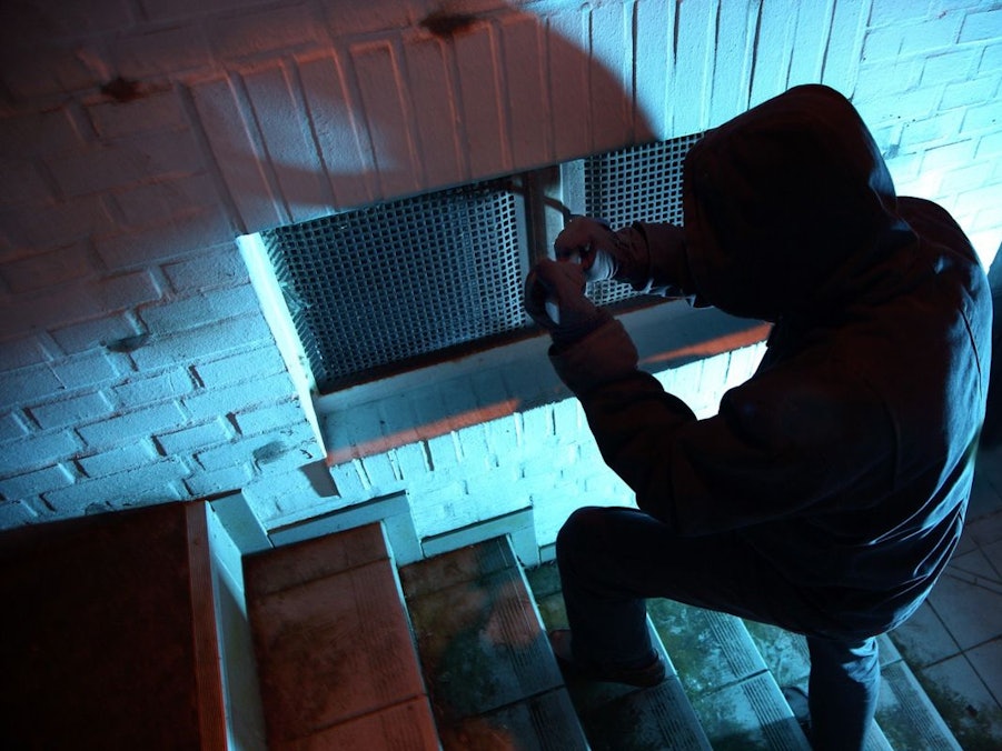 Einbrecher hebeln ein Kellerfenster auf.