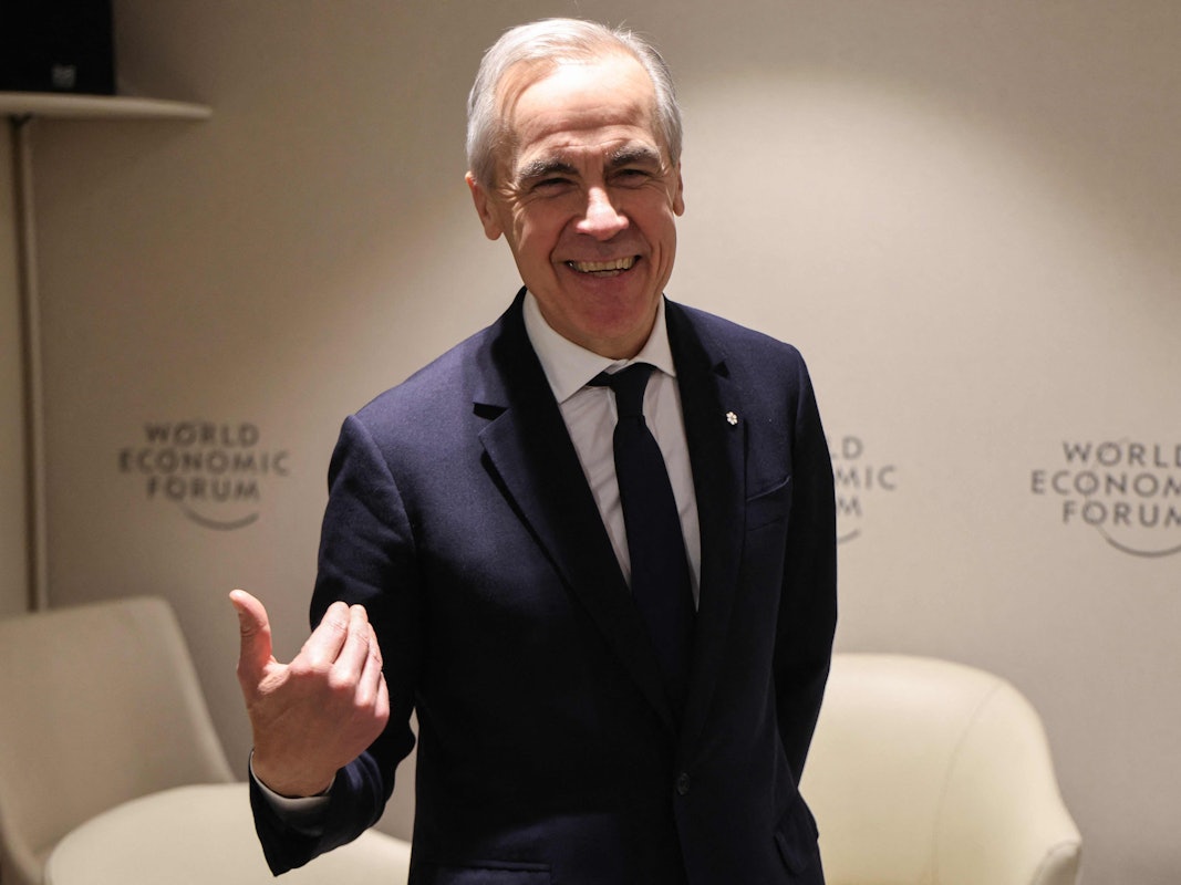 Ein Mann mit grauem Haar, in Anzug und mit Krawatte, gestikuliert und lacht dabei in die Kamera.