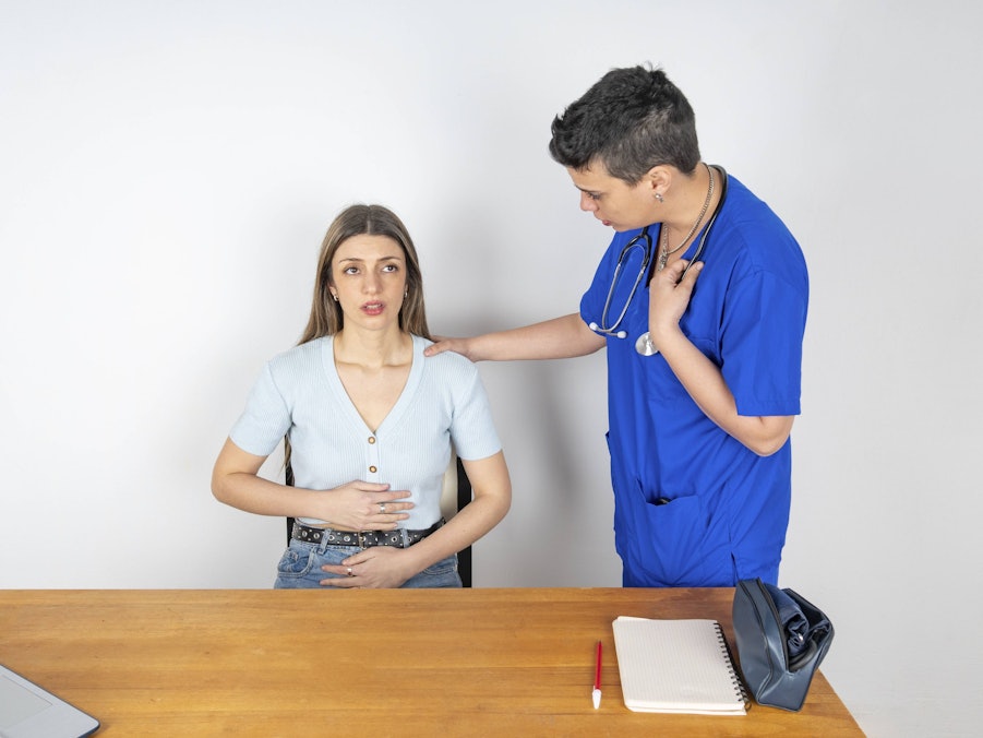 Arzt berät junge Frau mit Bauchschmerzen