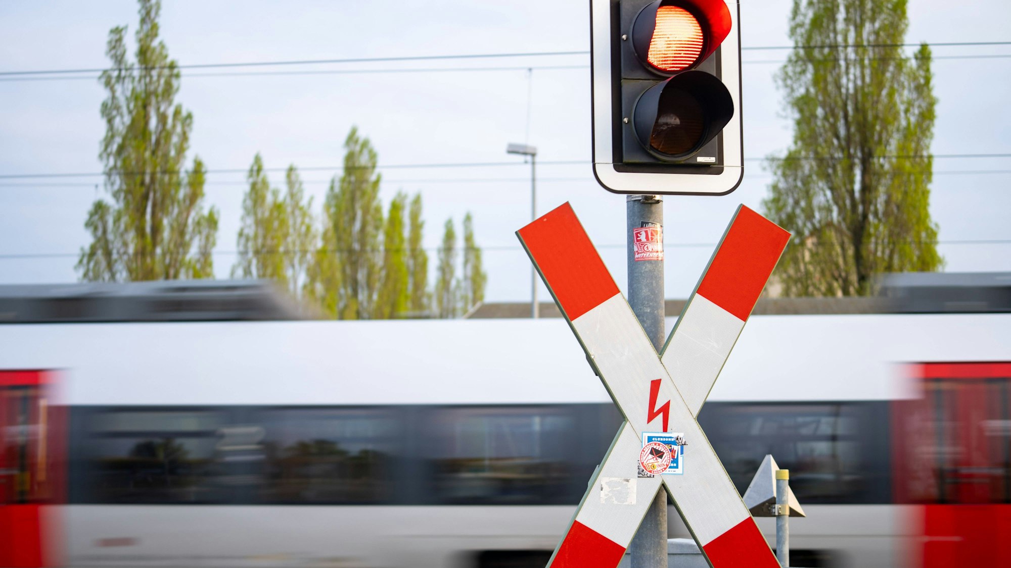 Bahnübergang mit Andreaskreuz, roter Ampel und Zug