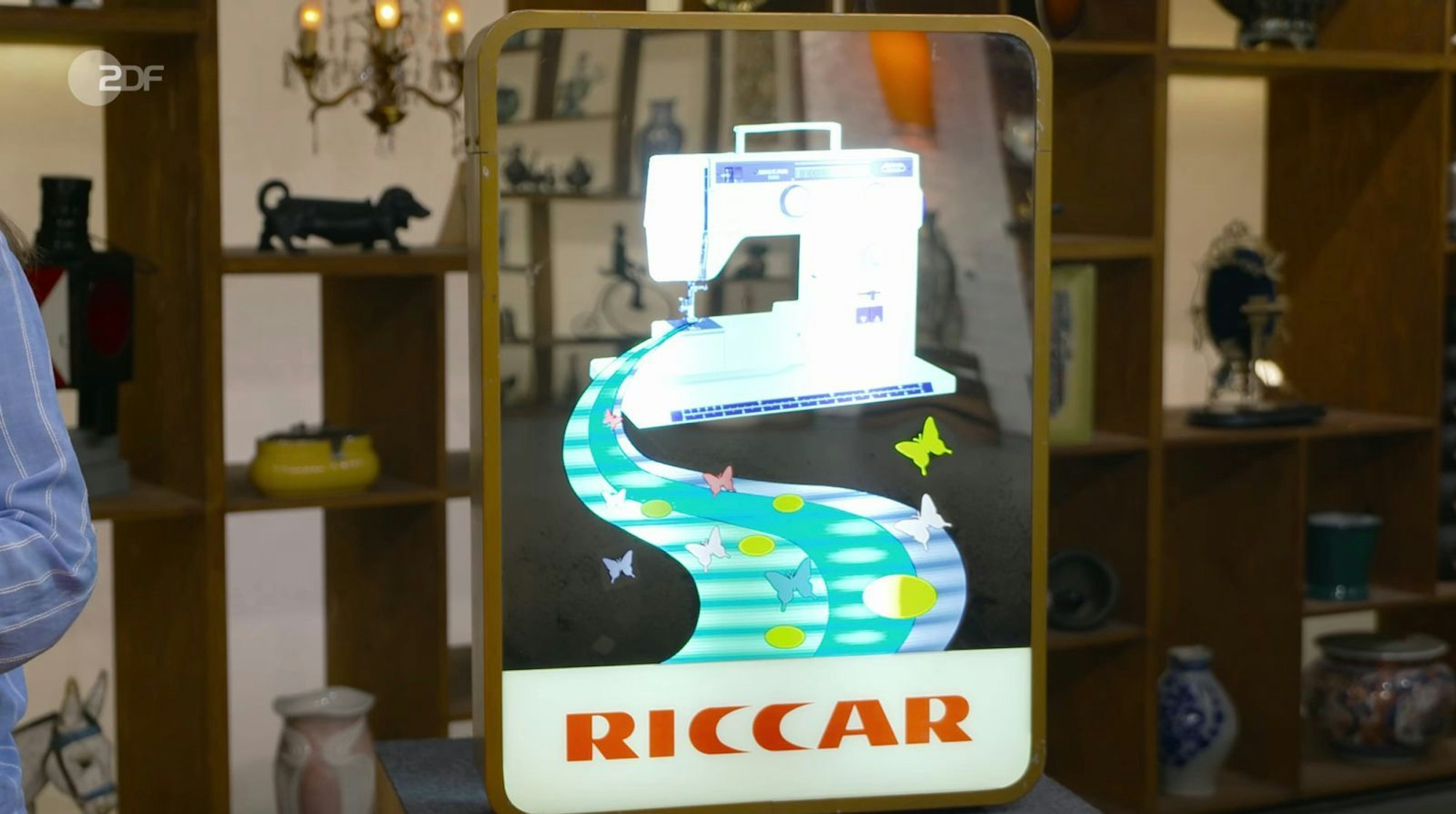 Für Kümmel war das schräge Objekt sogar mehr als bloße Werbung - er adelte es zum „Kunstwerk“. Denn die Reklame vereine gleich zwei Stilrichtungen: Kinetik, also bewegte Kunst, und Pop-Art. Selbst Andy Warhol habe Vergleichbares gemacht, laut Kümmel. „Aber der asiatische Geschmack hat es etwas verkitscht“, fügte er schnell hinzu. (Bild: ZDF)