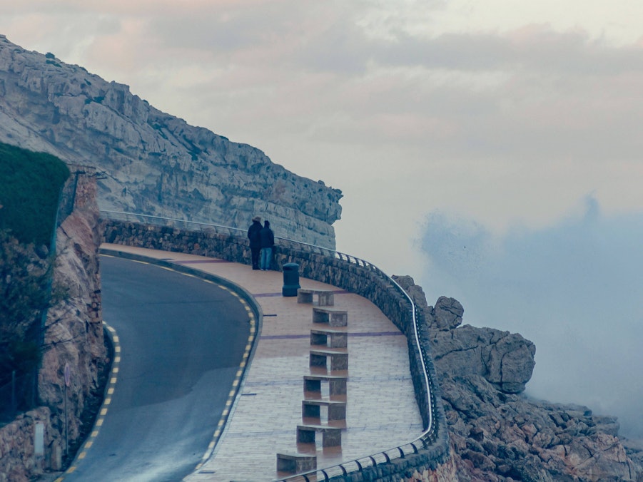Menschen auf Küstenstraße mit Felsen und Wellen