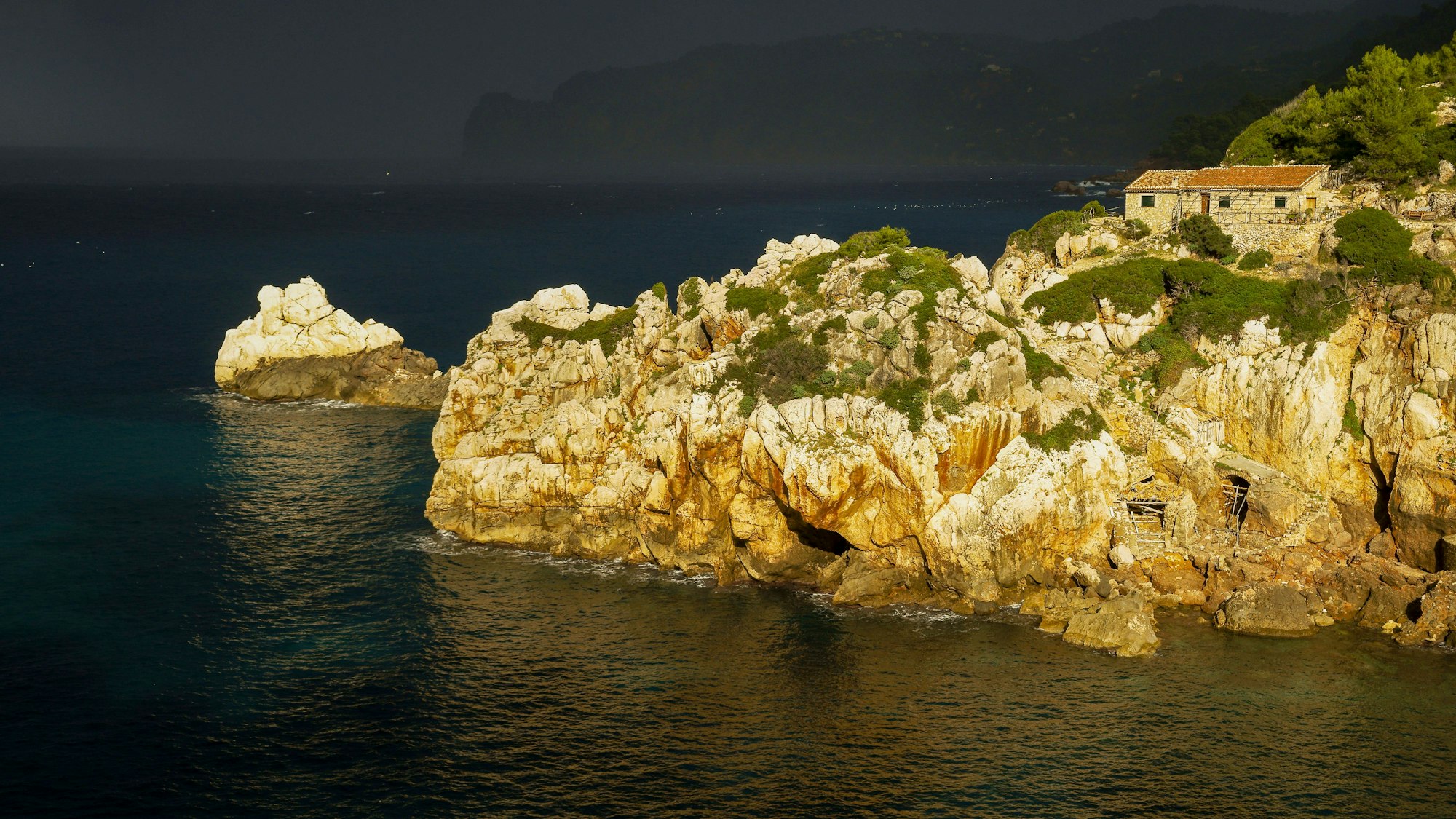 Küstenlandschaft mit Haus, Felsen und Sturm