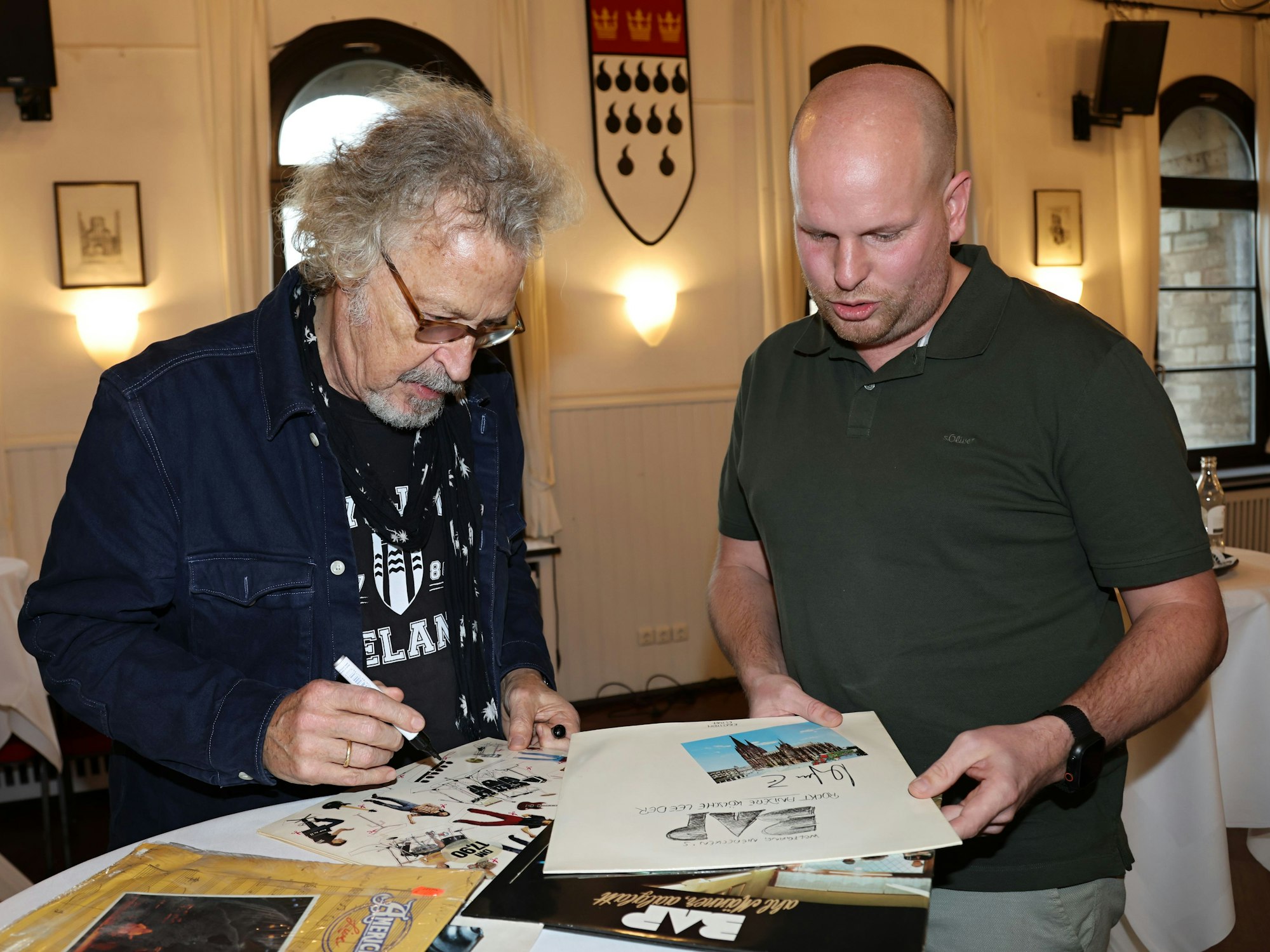 Wolfgang Niedecken unterschreibt Platten von Stefan Blatt.