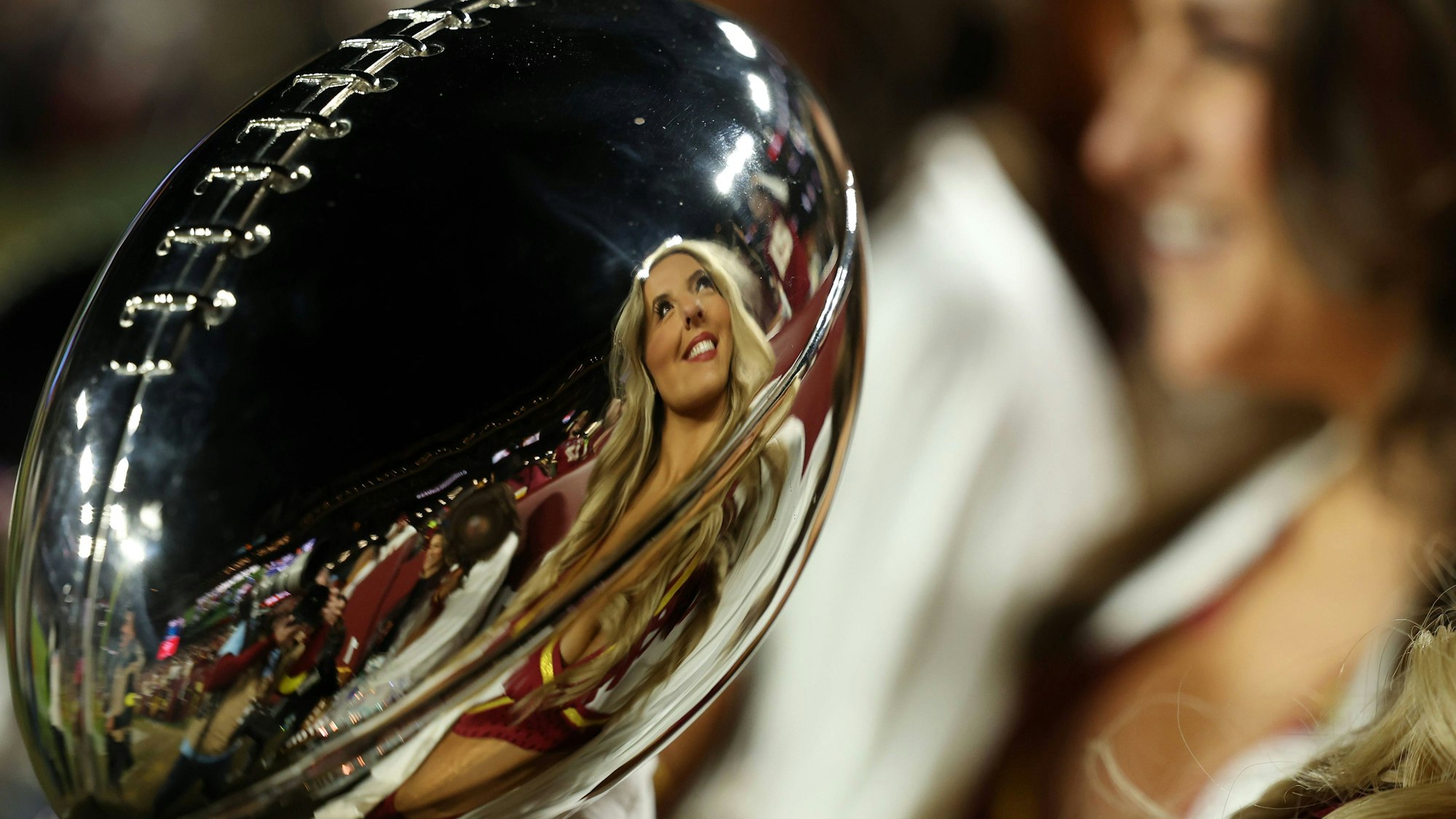 Eine Cheerleaderin spiegelt sich in der Super-Bowl-Trophäe.