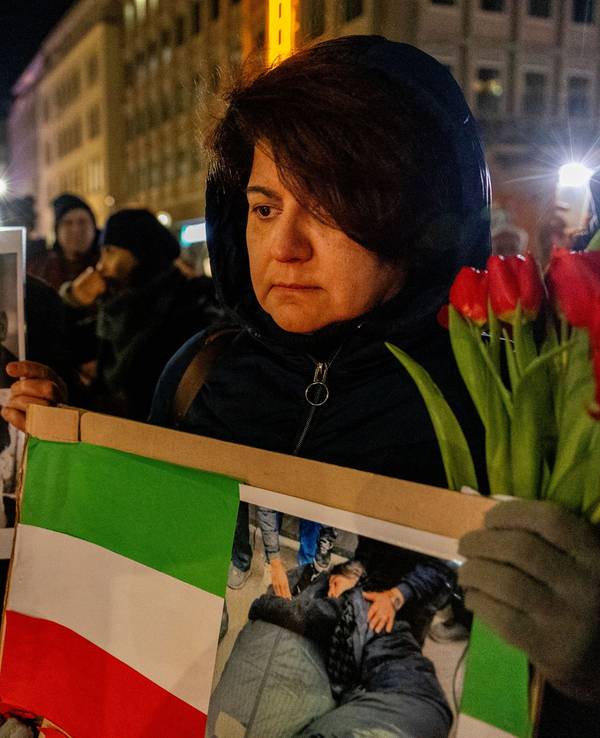 Trauernde Menschen mit Fotos Verstorbener und einer Iran-Flagge vor dem Dom.
