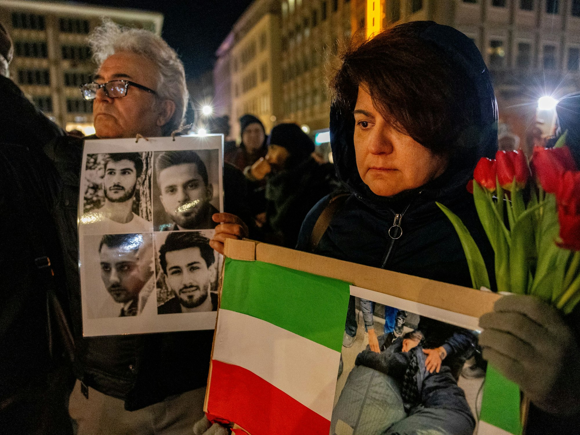 Trauernde Menschen mit Fotos Verstorbener und einer Iran-Flagge vor dem Dom.