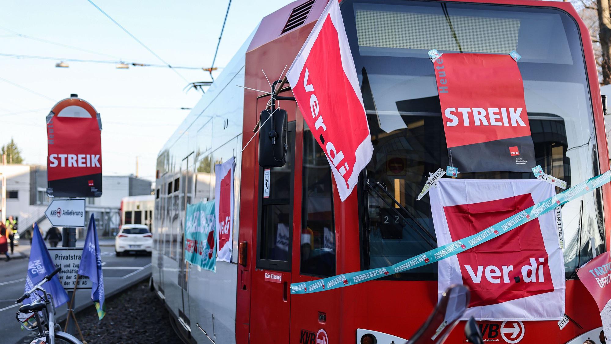 Eine mit Streik-Plakaten beklebte Straßenbahn der Kölner Verkehrs-Betriebe (KVB) steht vor dem Bahndepot.