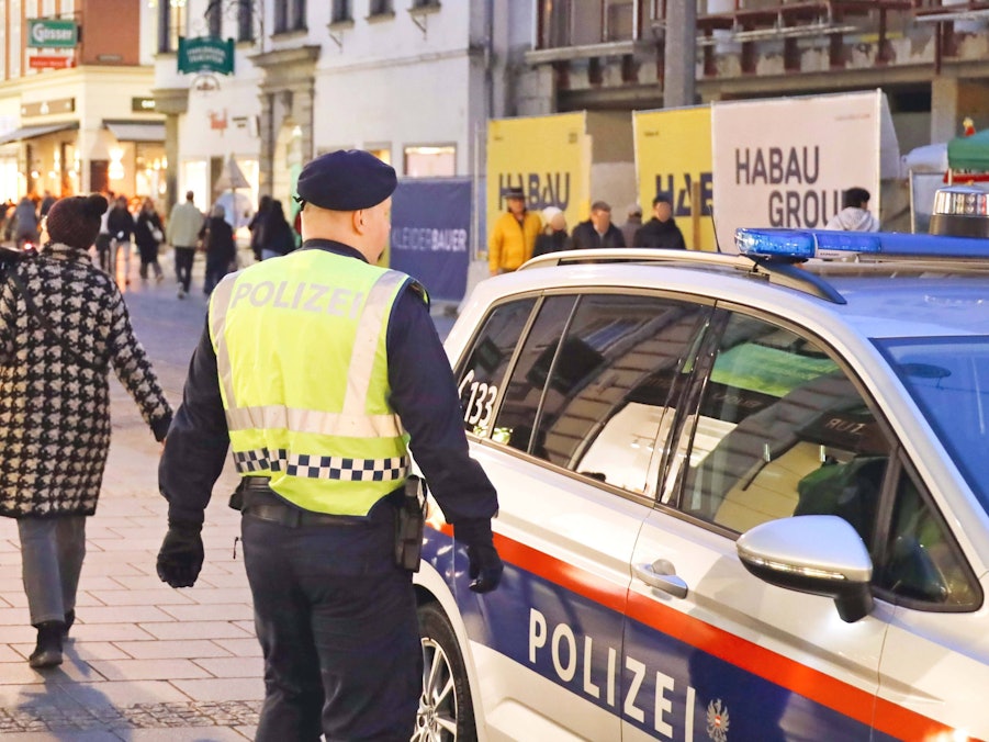 Polizist, Polizeiauto und Passanten auf Straße
