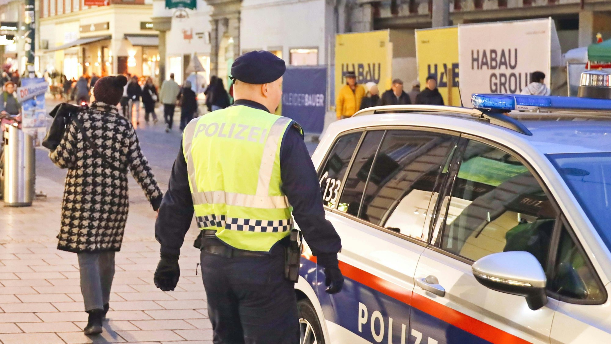 Polizist, Polizeiauto und Passanten auf Straße