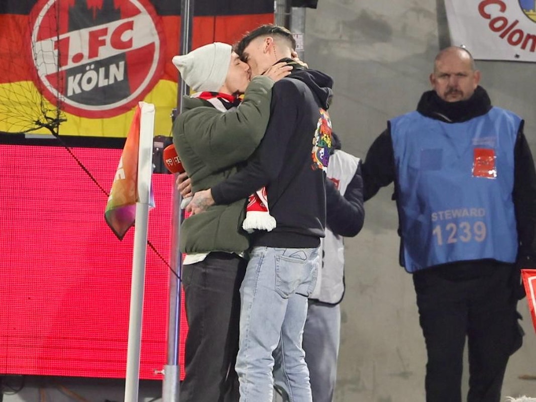 Zwei Männer küssen sich nach einem Heiratsantrag im FC-Stadion.