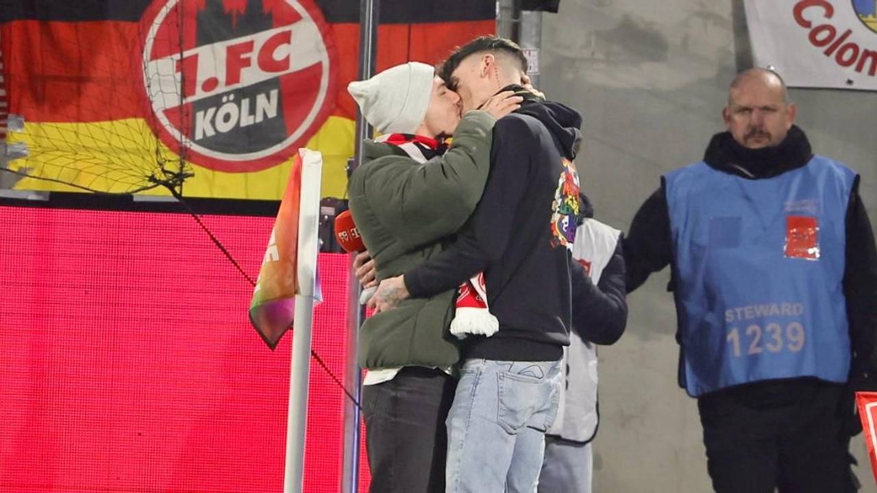 Zwei Männer küssen sich nach einem Heiratsantrag im FC-Stadion.
