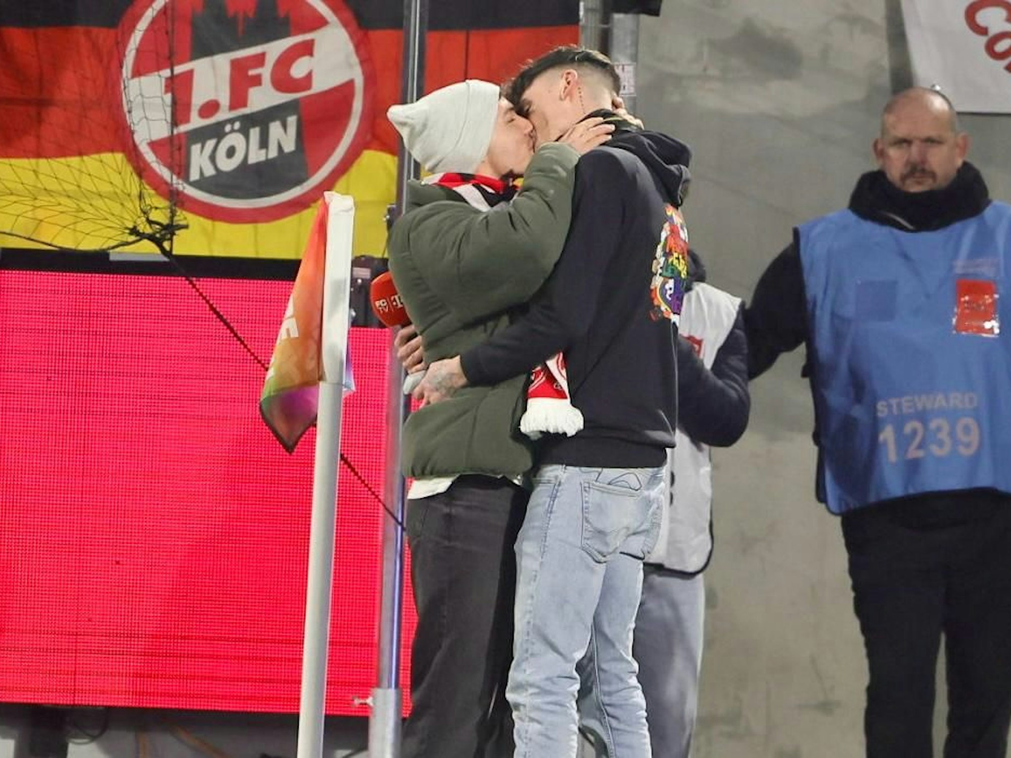 Zwei Männer küssen sich nach einem Heiratsantrag im FC-Stadion.