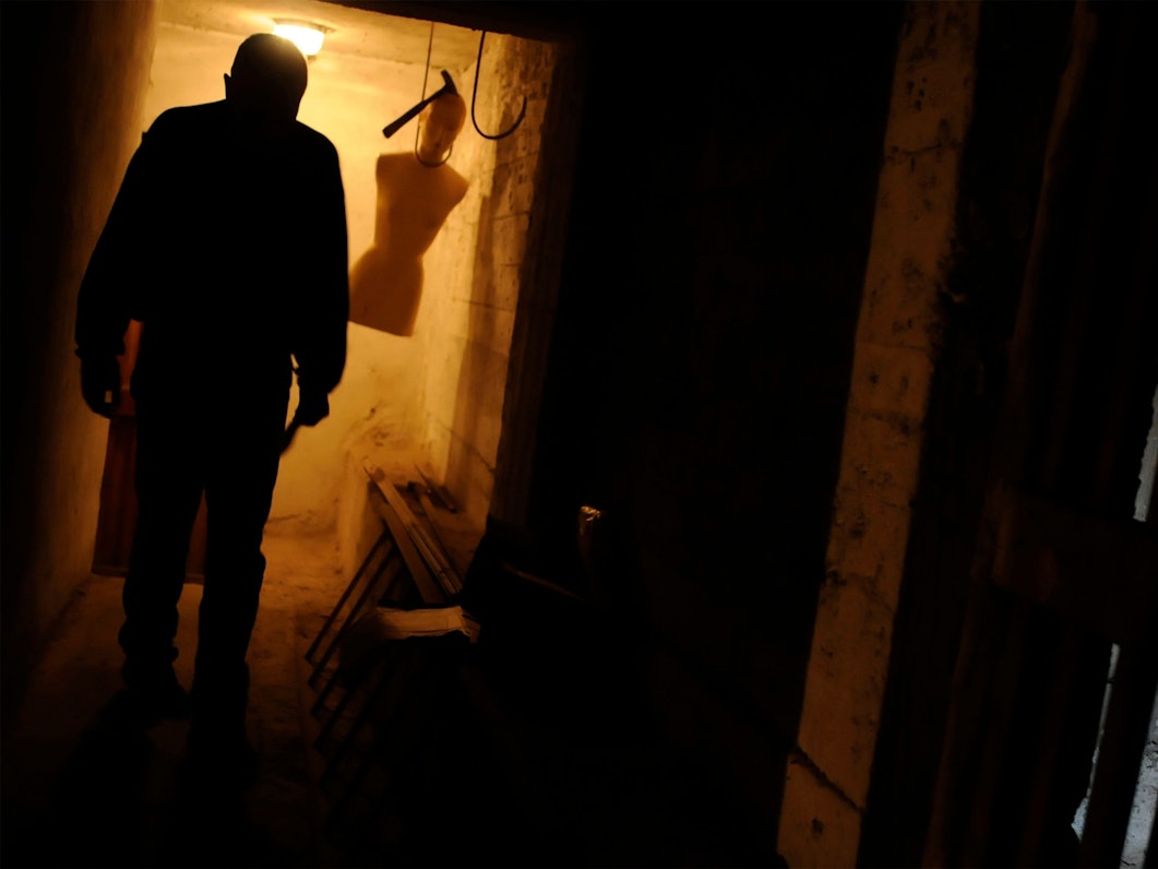 Schreckliche Szene – ein Verrückter in einem Keller mit einer hängenden Schaufensterpuppe.