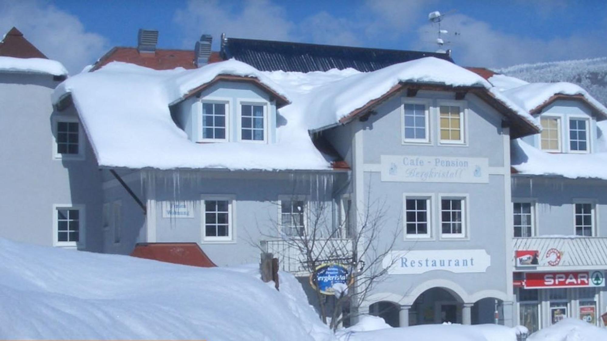 Ein hellblaues Hotelgebäude mit mehreren Erkern ist von einer dicken Schneedecke bedeckt.