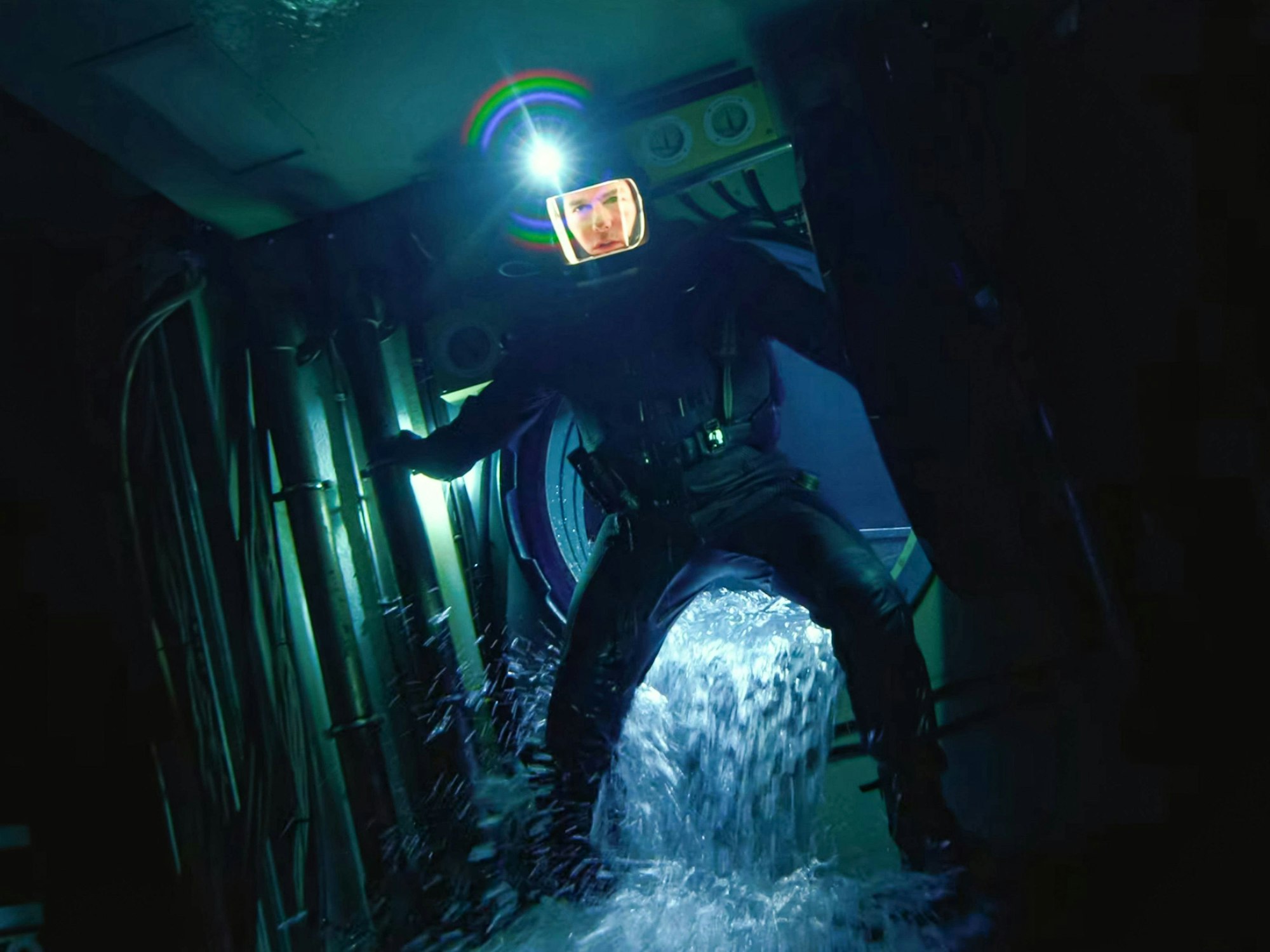 Ein Mann in einem dunklen Anzug mit einem Weltraumhelm watet durch eine dunkle Röhre, in die Wasser einströmt.