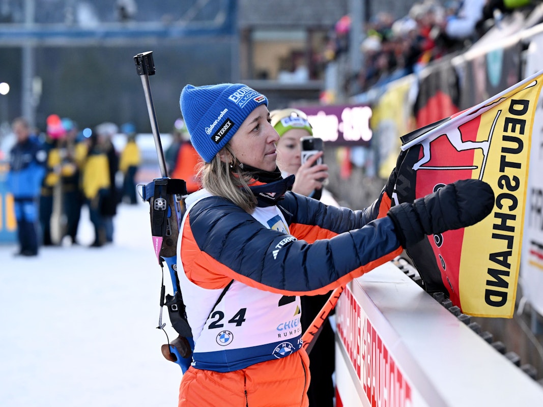 Franziska Preuß nimmt nach einem Biathlon-Rennen eine deutsche Fahne in die Hand.