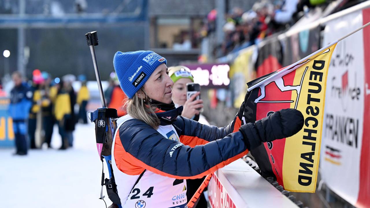 Franziska Preuß nimmt nach einem Biathlon-Rennen eine deutsche Fahne in die Hand.