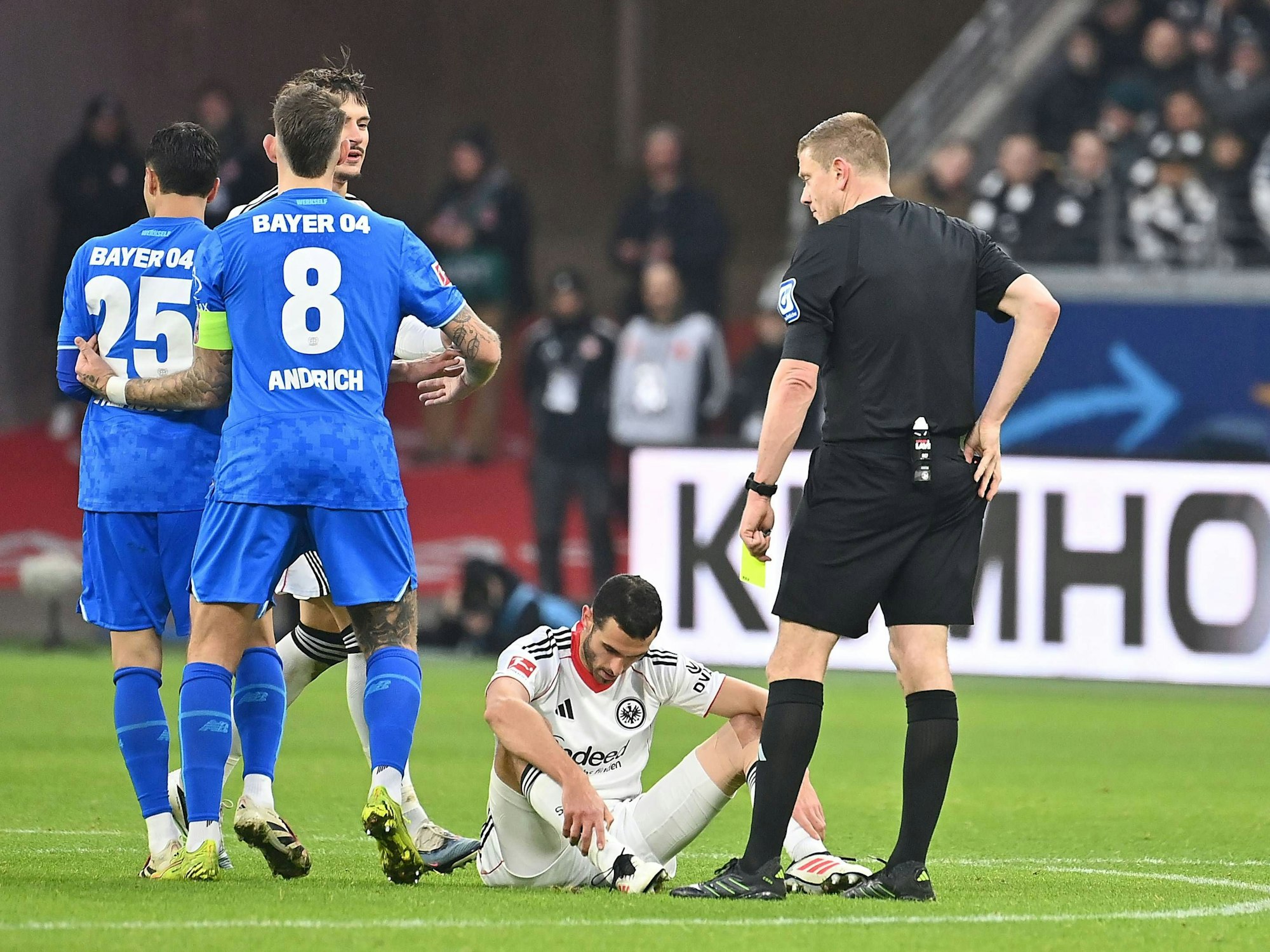 Ellyes Skhiri sitzt auf dem Rasen, der Schiedsrichter hält in der linken Hand die Gelbe Karte und holt aus seiner Gesäßtasche die Rote Karte.
