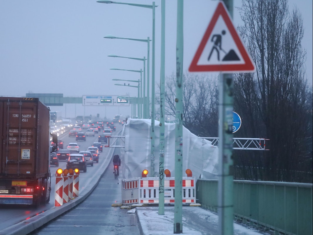 Auf einer Brücke fährt der Verkehr an kleinen Zelten vorbei, die an der Seite stehen.