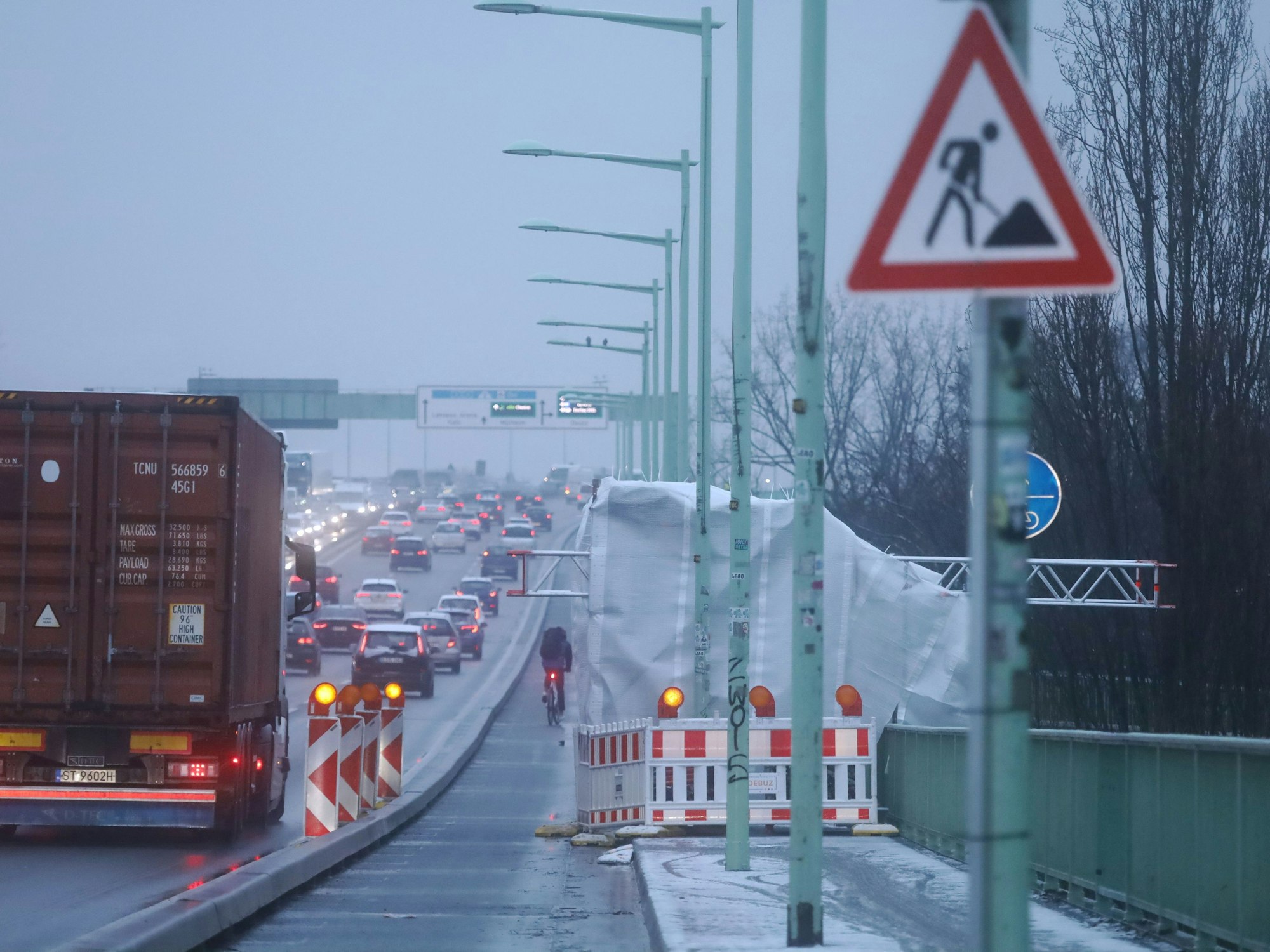 Auf einer Brücke fährt der Verkehr an kleinen Zelten vorbei, die an der Seite stehen.