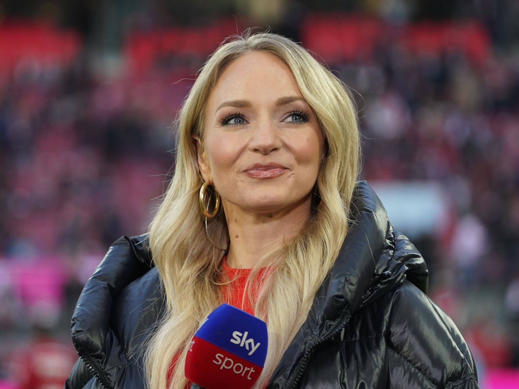 Katharina Kleinfeldt lächelt und hält ein Sky-Mikrofon in der Hand.