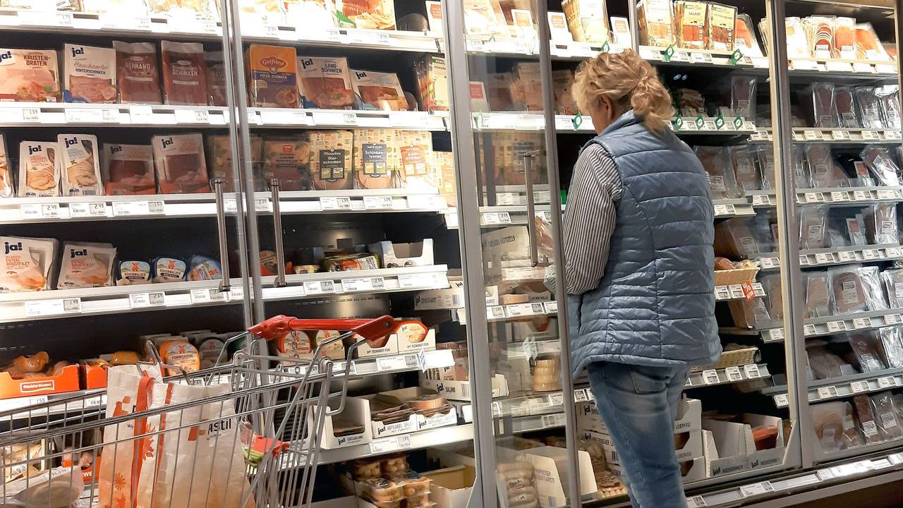 Eine Frau steht vor der Kühltheke in einem Rewe-Markt und schaut nach Wurstsorten. (Symbolfoto)