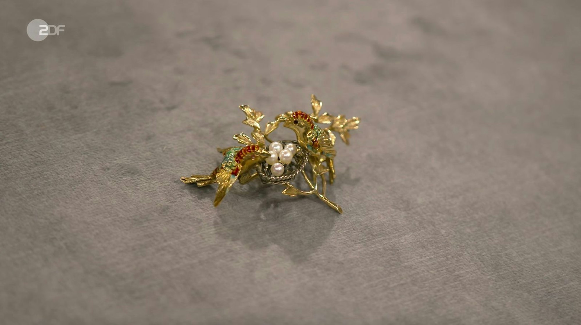 Eine Brosche samt Vogelpaar mit Nest aus 750er Gold, Silber und Emaille mit Zuchtperlen datierte Heide Rezepa-Zabel in den 1950er Jahren. Der Wunschpreis lag bei 800 bis 900 Euro. Die Expertin schätzte ebenfalls 800 bis 1.000 Euro und Händlerin Elke Velten zahlte 900 Euro. (Bild: ZDF)