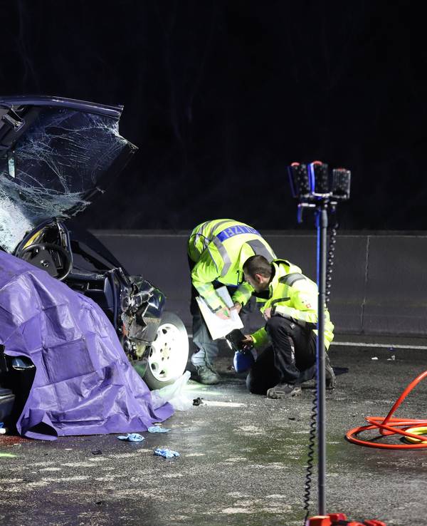 Einsatzkräfte der Polizei untersuchen ein Unfallfahrzeug. +
