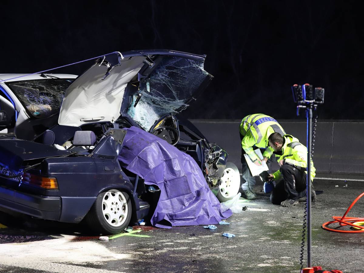 Einsatzkräfte der Polizei untersuchen ein Unfallfahrzeug. +