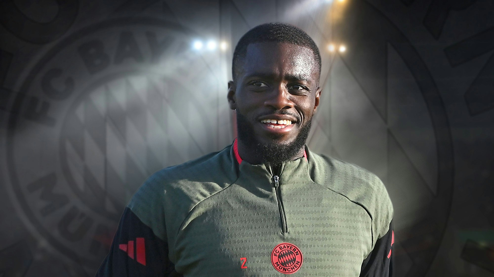 Dayot Upamecano vor dem Bayern-Logo in Trainingsklamotten des Rekordmeisters.