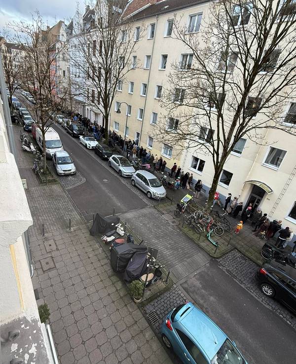 Menschen stehen auf einem Bürgersteig Schlange.