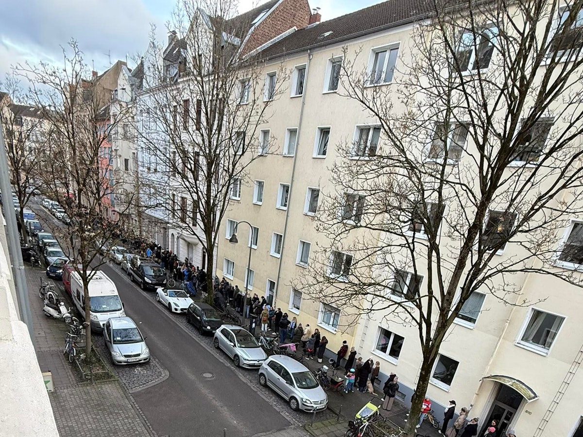 Menschen stehen auf einem Bürgersteig Schlange.