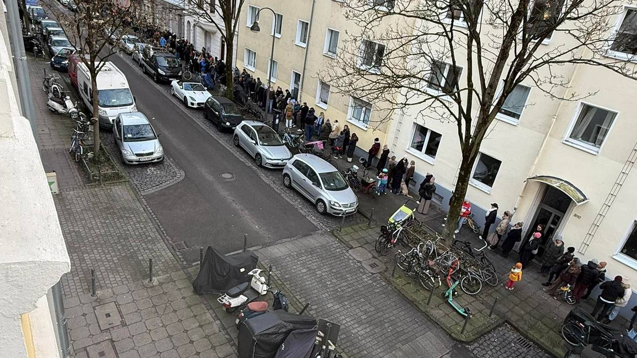 Menschen stehen auf einem Bürgersteig Schlange.
