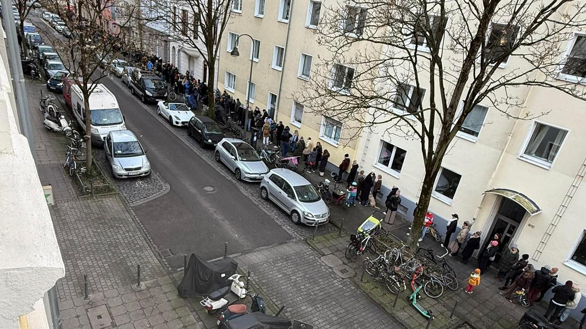 Menschen stehen auf einem Bürgersteig Schlange.