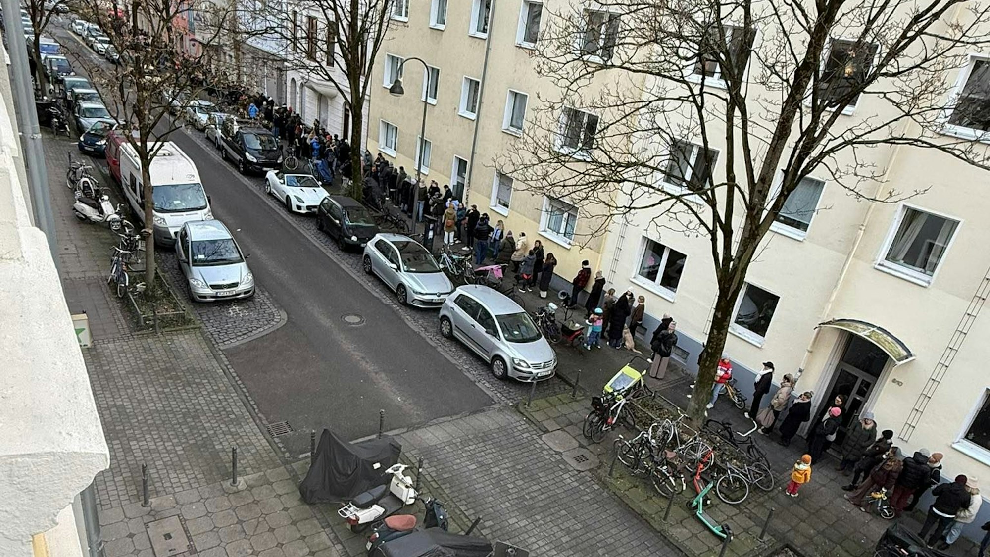 Menschen stehen auf einem Bürgersteig Schlange.
