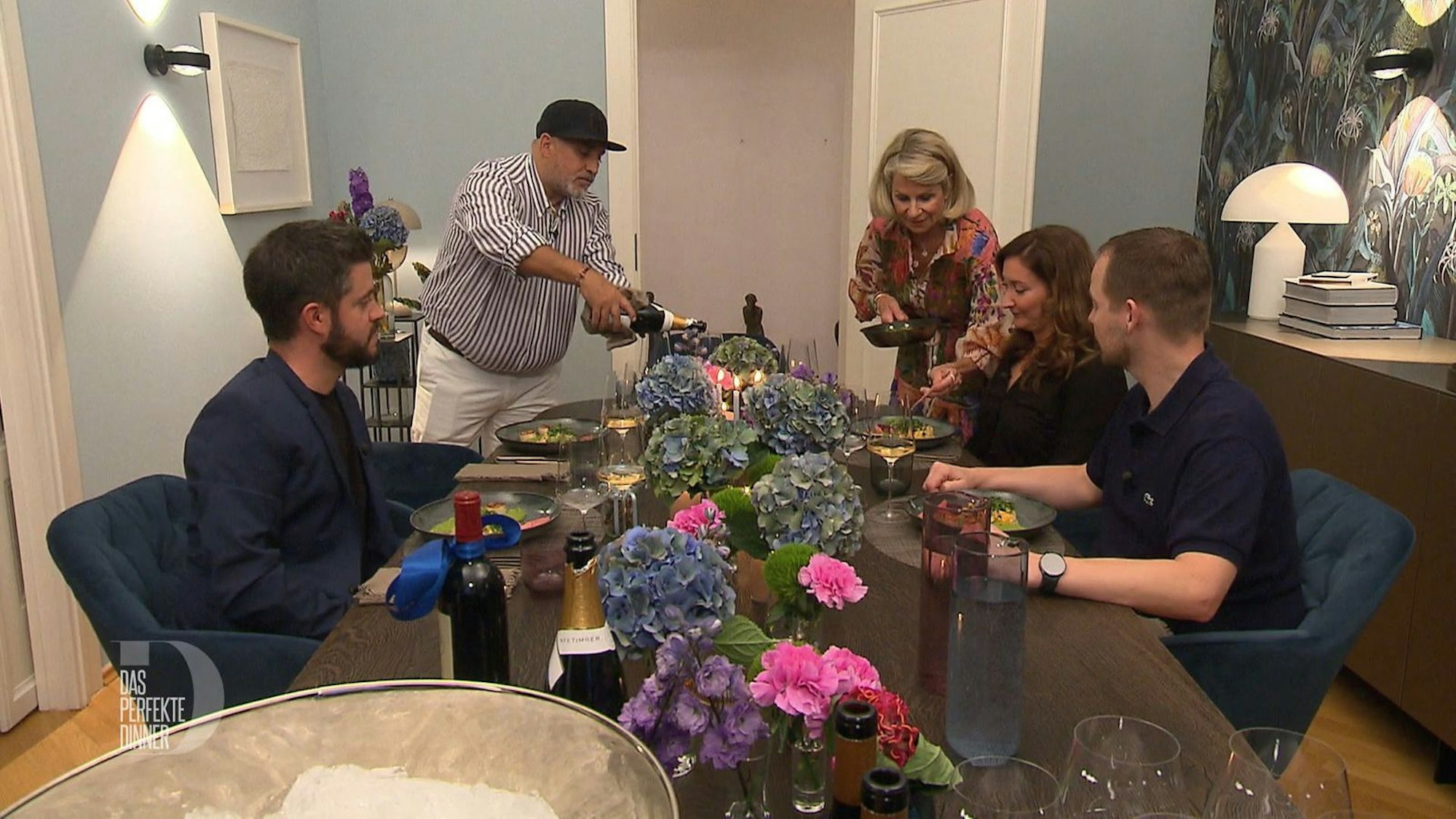 Während Martina noch schnell eine vergessene Komponente auf die Teller platziert, betätigt sich Musti als Sommelier.
(Bild: RTL)