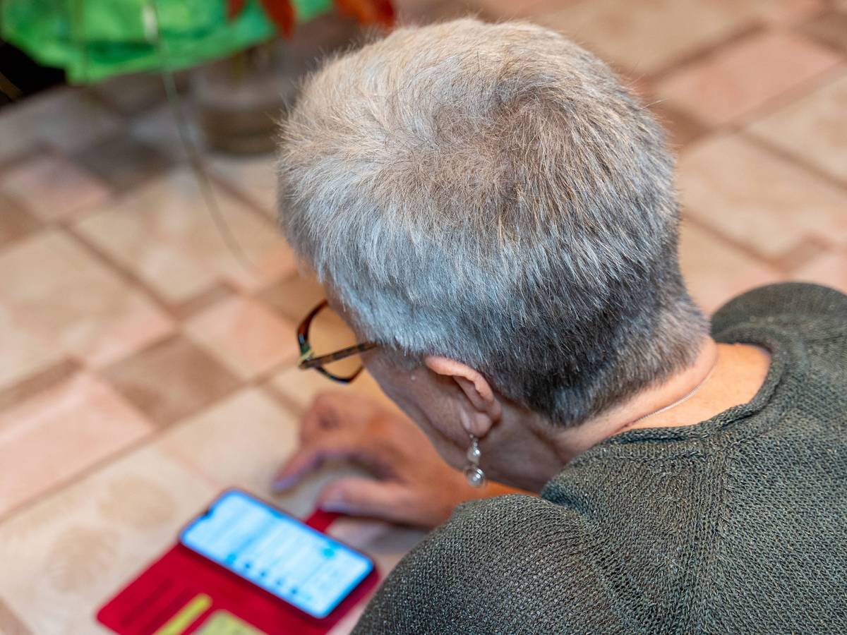 Ältere Frau tippt auf Smartphone am Tisch
