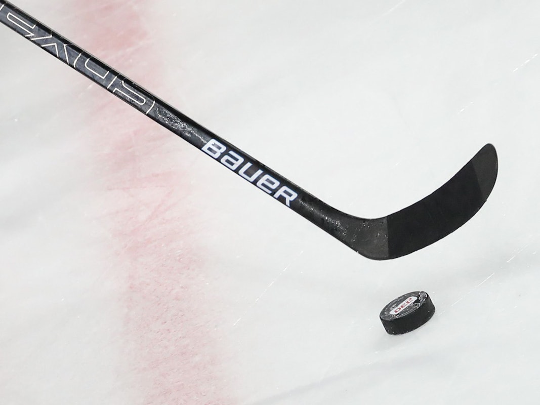 Ein Puck liegt vor einem Schläger im Spiel auf dem Eis.