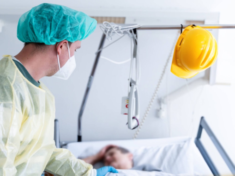 Arbeitsunfall: Pflegekraft, Patient und Bauhelm