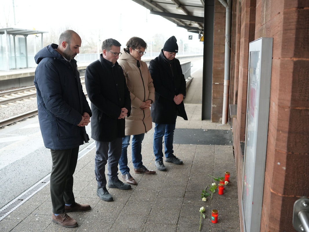 Menschen stehen vor Blumen und Kerzen am Bahnsteig im Gedenken an den Tod eines Zugbegleiters. Der Mann war bei einem Angriff im Zug von einem Fahrgast am Montagabend in Rheinland-Pfalz lebensgefährlich verletzt worden und am Morgen infolge der Verletzungen verstorben.